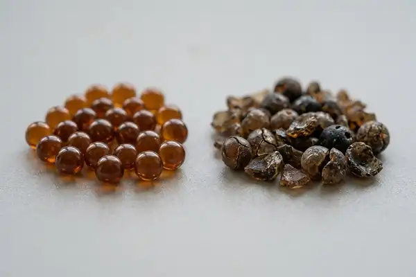 Healthy amber ion-exchange resin beads next to cracked, worn resin beads from a failed water softener